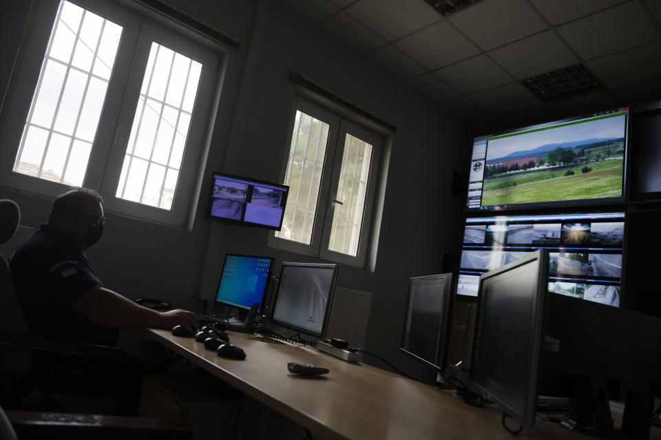 A police officer works inside the operation center at the village of Nea Vyssa near the Greek - Turkish border, Greece, Friday, May 21, 2021. An automated hi-tech surveillance network being built on the Greek-Turkish border aiming at detecting migrants early and deterring them from crossing, with river and land patrols using searchlights and long-range acoustic devices. (AP Photo/Giannis Papanikos)