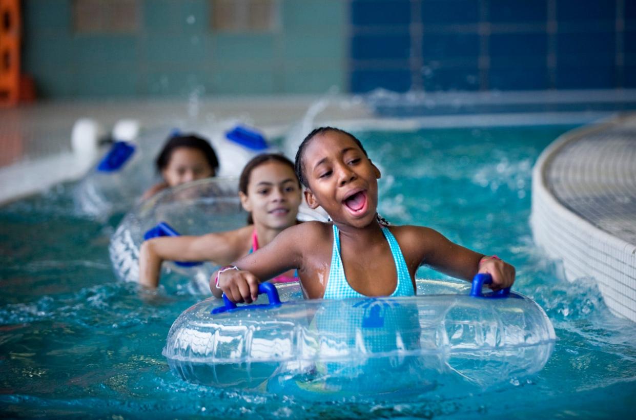 India Harris leads friends Tia Newell and her sister Emily Newell in a paddle Thursday at the Aquaplex in the RiverPlex Recreation and Wellness Center. They were among 17 children at a RiverPlex camp who were joined by dozens of other children for open swim offered by the Peoria Park District.