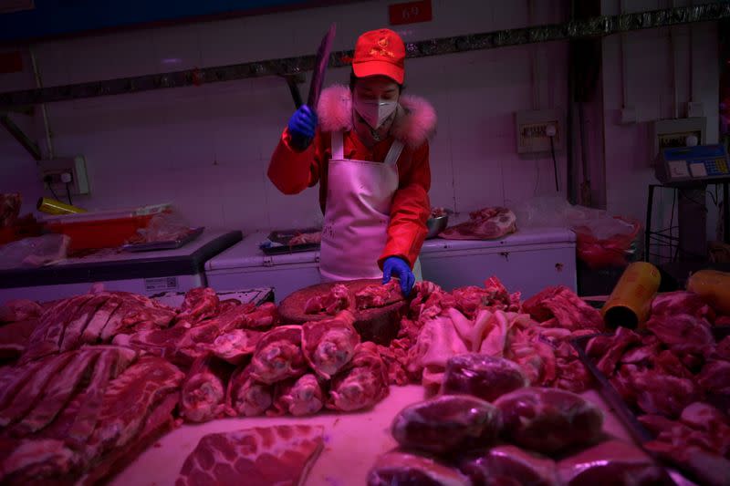 FILE PHOTO: Employee chops pork meat at the Xinfadi wholesale market, as the country is hit by an outbreak of the novel coronavirus disease (COVID-19), in Beijing