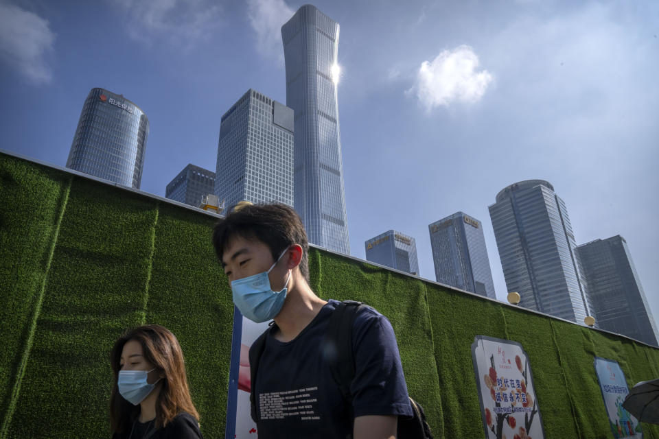 FILE - Commuters wearing face masks walk along a street in the central business district in Beijing on July 29, 2022. By 2035, the Communist Party wants economic output per person to match a "medium-level developed country," Chinese President Xi said in a report to the 20th National Party Congress. (AP Photo/Mark Schiefelbein, File)