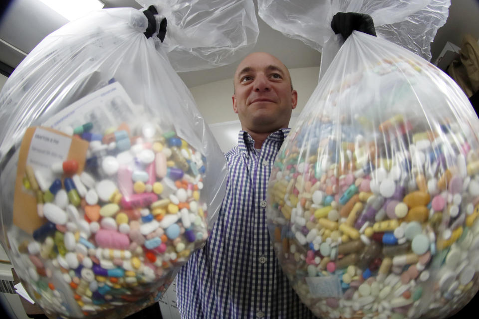 FILE - In this Wednesday, Sept. 11, 2019, file photo, narcotics detective Ben Hill, with the Barberton Police Department, shows two bags of medications that are are stored in their headquarters and slated for destruction in Barberton, Ohio. Jury selection is set to begin Wednesday, Oct. 16, 2019, in the first federal trial over the nation's opioid epidemic. (AP Photo/Keith Srakocic, File)