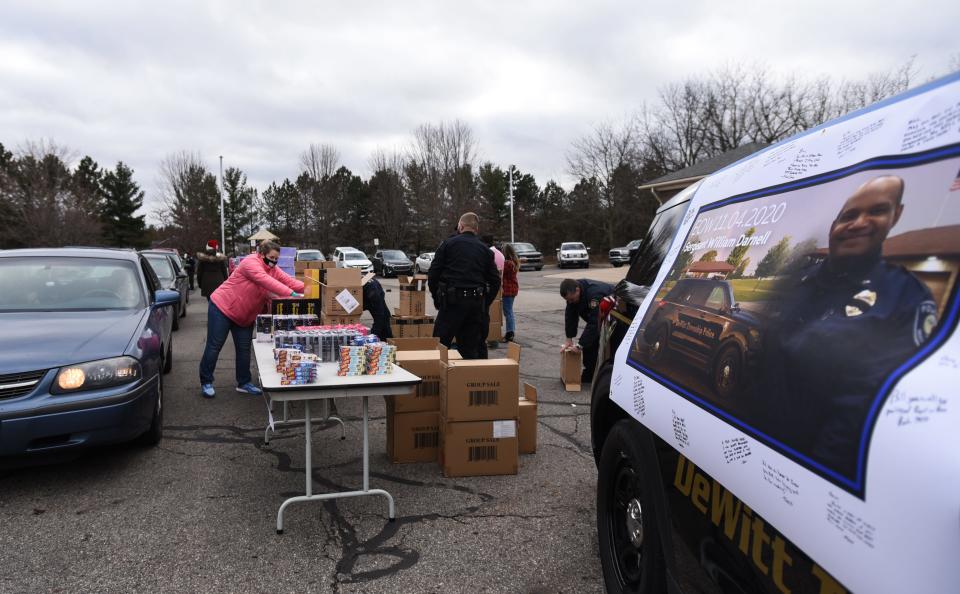 Cars line up during a toy giveaway, Tuesday outside the DeWitt Township Fire Department in Michigan. The gifts were donated by the First Responders Children's Foundation, to be handed out to the community in honor of Sgt. Bill Darnell,  pictured at right, who died Nov. 4 after a short fight with COVID-19.