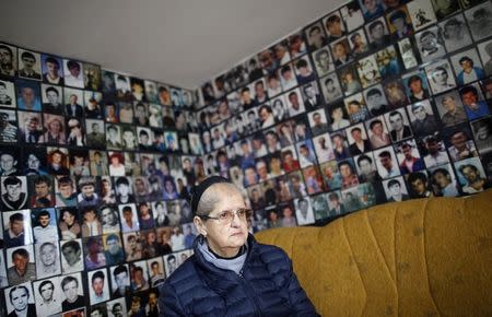 Hajra Catic poses under pictures of victims of the genocide in Tuzla, December 23, 2014. REUTERS/Dado Ruvic