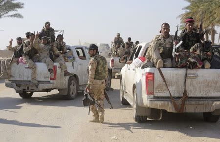 Shi'ite fighters and Iraqi army members ride in vehicles during a patrol in Jurf al-Sakhar October 25, 2014. REUTERS/Stringer