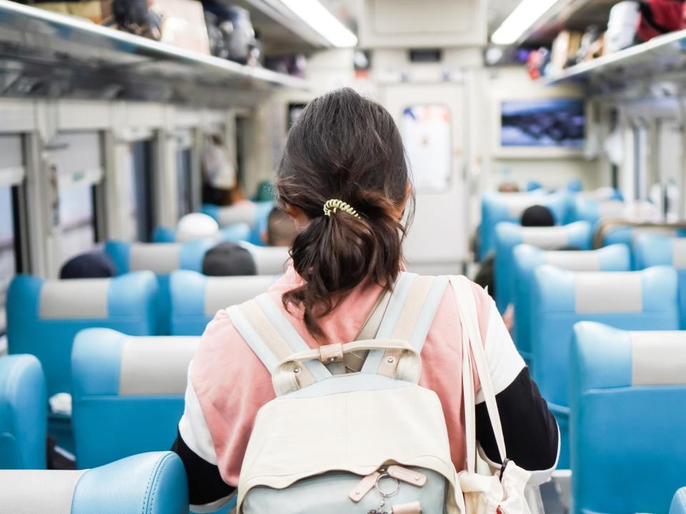 Frau auf dem Weg zu ihrem Sitzplatz in einem Zug.