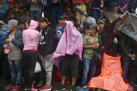 Honduran migrants, part of a caravan trying to reach the U.S., protect themselves from torrential rain during a new leg of their travel in Mazatenango, Guatemala October 18, 2018. REUTERS/Edgard Garrido