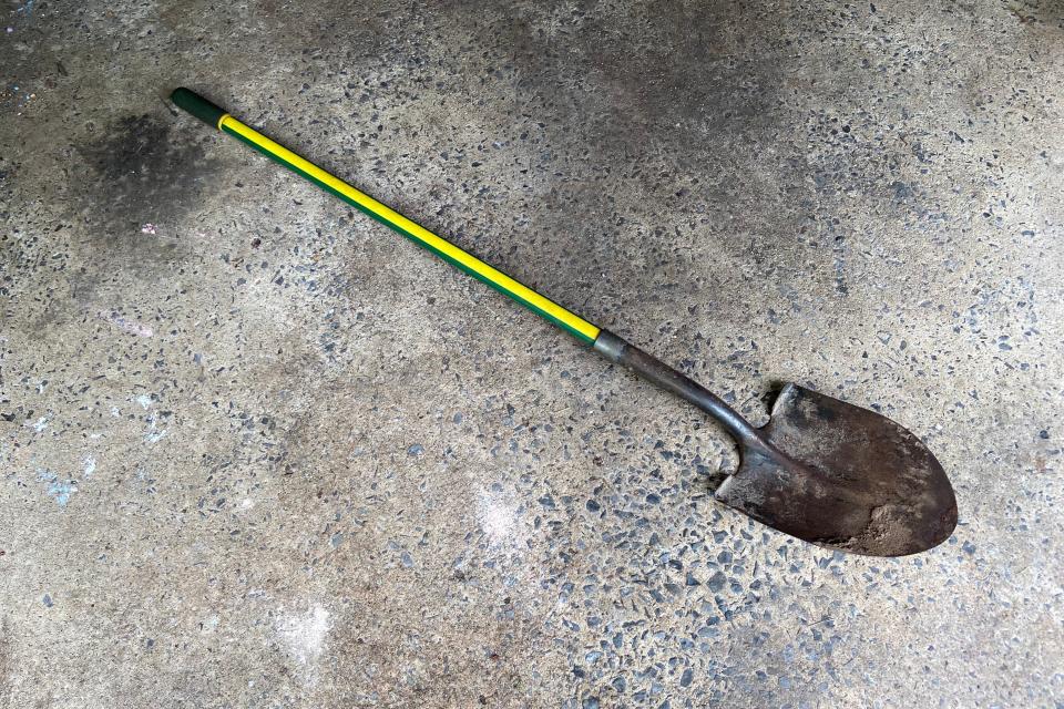 A garden shovel lying diagonally on concrete