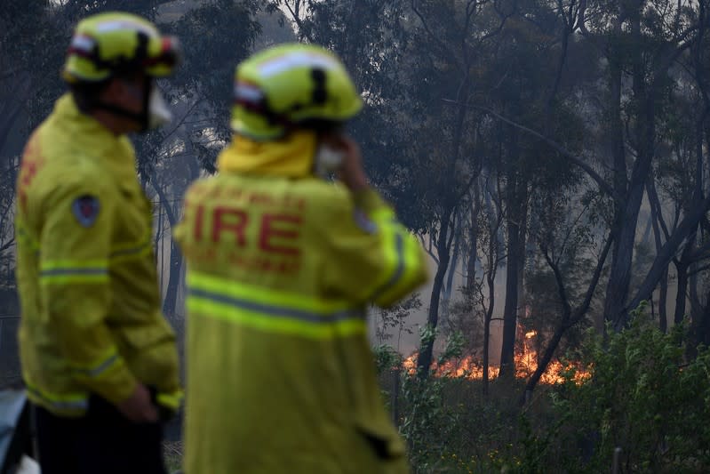 NSW Rural Fire Service and Fire and Rescue NSW personnel conduct property protection as a bushfire burns in Woodford NSW