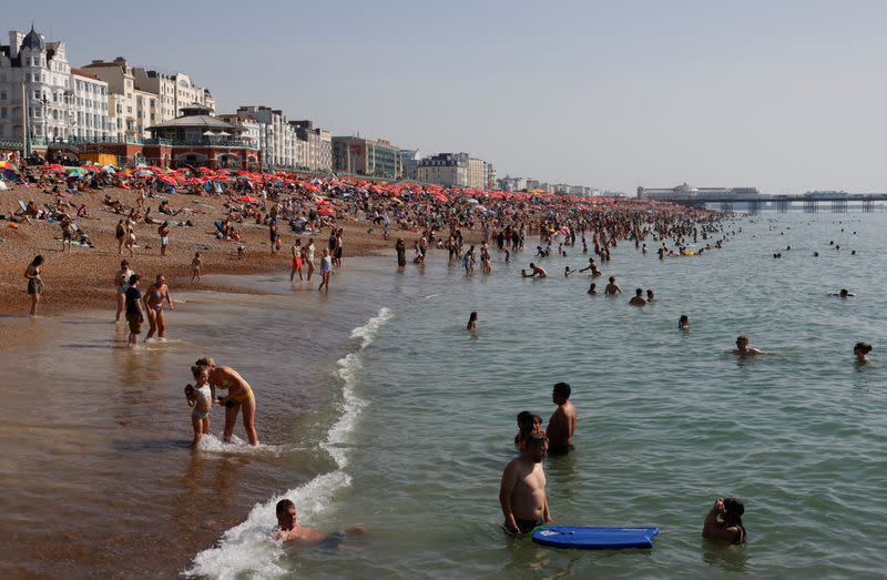 Beachgoers cool off in the water during hot weather in Brighton