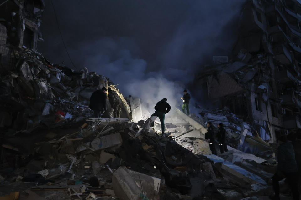 Emergency workers clear the rubble after a Russian rocket hit a multistory building leaving many people under debris in Dnipro, Ukraine, Saturday, Jan. 14, 2023. (AP Photo/Roman Chop)