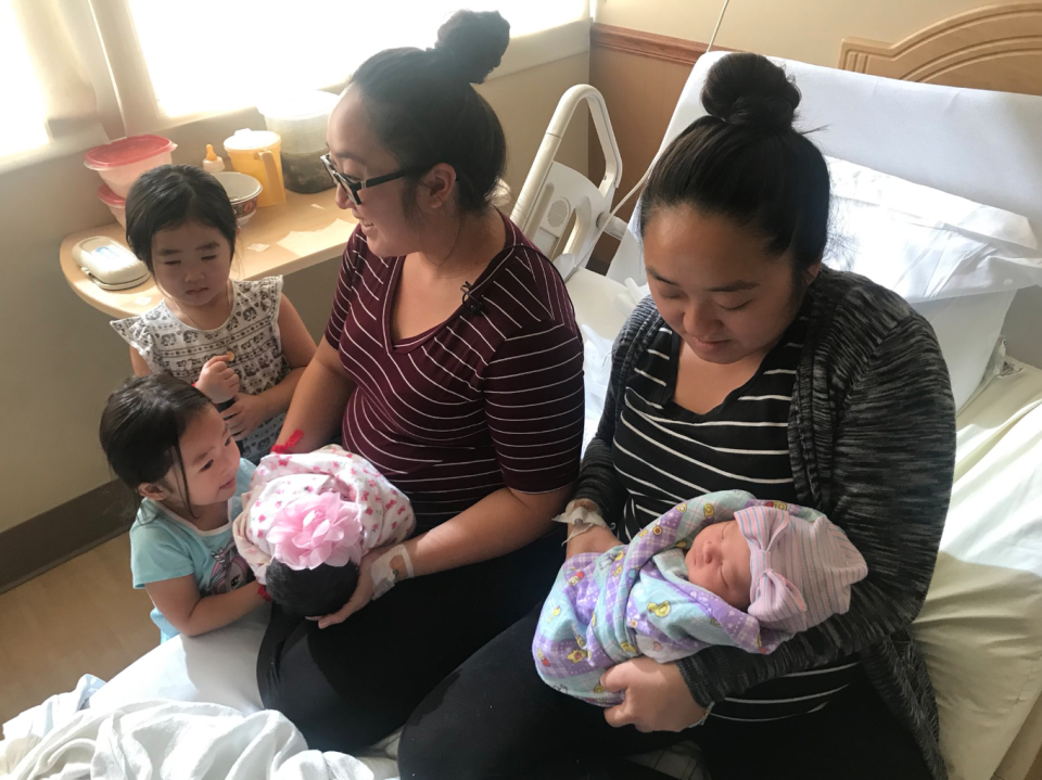 Twin sisters <span>Bao Nhia Julia Yang and Bao Kou Julie Yang hold their newborn daughters while Bao Nhia’s two older children look on. </span>(Photo: @MissConnieTran via Twitter)