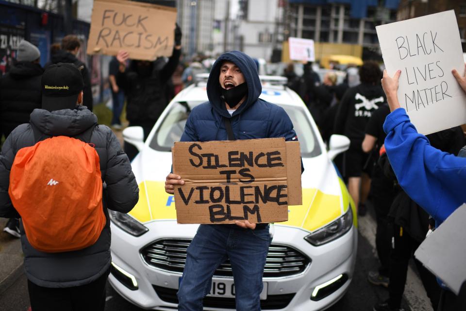 A protesters holds a placard in front of a police car during a march in central London on June 6, 2020, to show solidarity with the Black Lives Matter movement in the wake of the killing of George Floyd, an unarmed black man who died after a police officer knelt on his neck in Minneapolis. - Taking a knee, chanting and ignoring social distancing measures, outraged protesters from Sydney to London kicked off a weekend of global rallies Saturday against racism and police brutality. (Photo by DANIEL LEAL-OLIVAS / AFP) (Photo by DANIEL LEAL-OLIVAS/AFP via Getty Images)