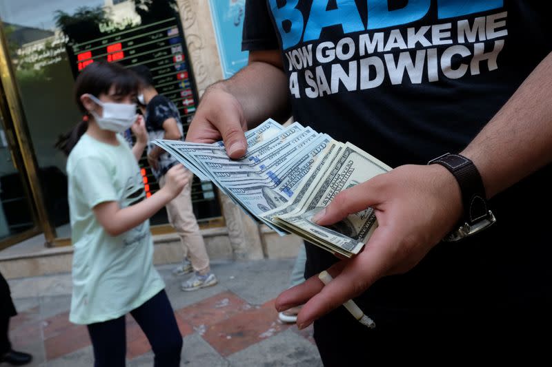 An unauthorised seller counts U.S. dollars in front of an Exchange shop at Ferdowsi square in Tehran