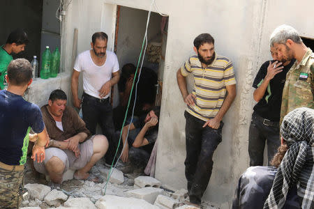 Men mourn the death of their relatives after an airstrike in the rebel held Bab al-Nairab neighborhood of Aleppo, Syria, August 25, 2016. REUTERS/Abdalrhman Ismail