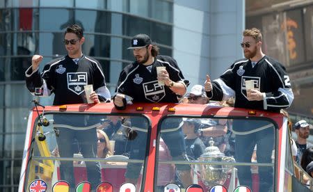 Los Angeles Kings players Alec Martinez (27), Drew Doughty (8) and Trevor Lewis (22) wave to the crowd during a parade on Figueroa Street to celebrate winning the 2014 Stanley Cup. Mandatory Credit: Kirby Lee-USA TODAY Sports
