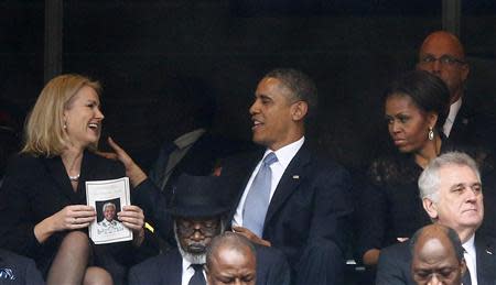 U.S. President Barack Obama (C) shares a moment with Denmark's Prime Minister Helle Thorning-Schmidt (L) as his wife, first lady Michelle Obama looks on (R) during the memorial service for late South African President Nelson Mandela at the First National Bank stadium, also known as Soccer City, in Johannesburg December 10, 2013.REUTERS/Kai Pfaffenbach