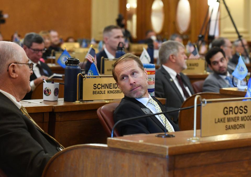 Representative Scott Odenbach leans over to talk with Representative Randy Gross during the first day of the legislative session on Tuesday, January 11, 2022, at the South Dakota State Capitol in Pierre.