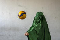 An Afghan volleyball player poses for a photo in Kabul, Afghanistan, Saturday, Sept. 17, 2022. The ruling Taliban have banned women from sports as well as barring them from most schooling and many realms of work. A number of women posed for an AP photographer for portraits with the equipment of the sports they loved. Though they do not necessarily wear the burqa in regular life, they chose to hide their identities with their burqas because they fear Taliban reprisals and because some of them continue to practice their sports in secret. (AP Photo/Ebrahim Noroozi)
