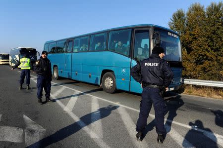 Greek police officers direct buses carrying hundreds of migrants, who were stranded on the Greek-Macedonian border and blocked rail traffic, after a police operation near the village of Idomeni, Greece, December 9, 2015. REUTERS/Alexandros Avramidis