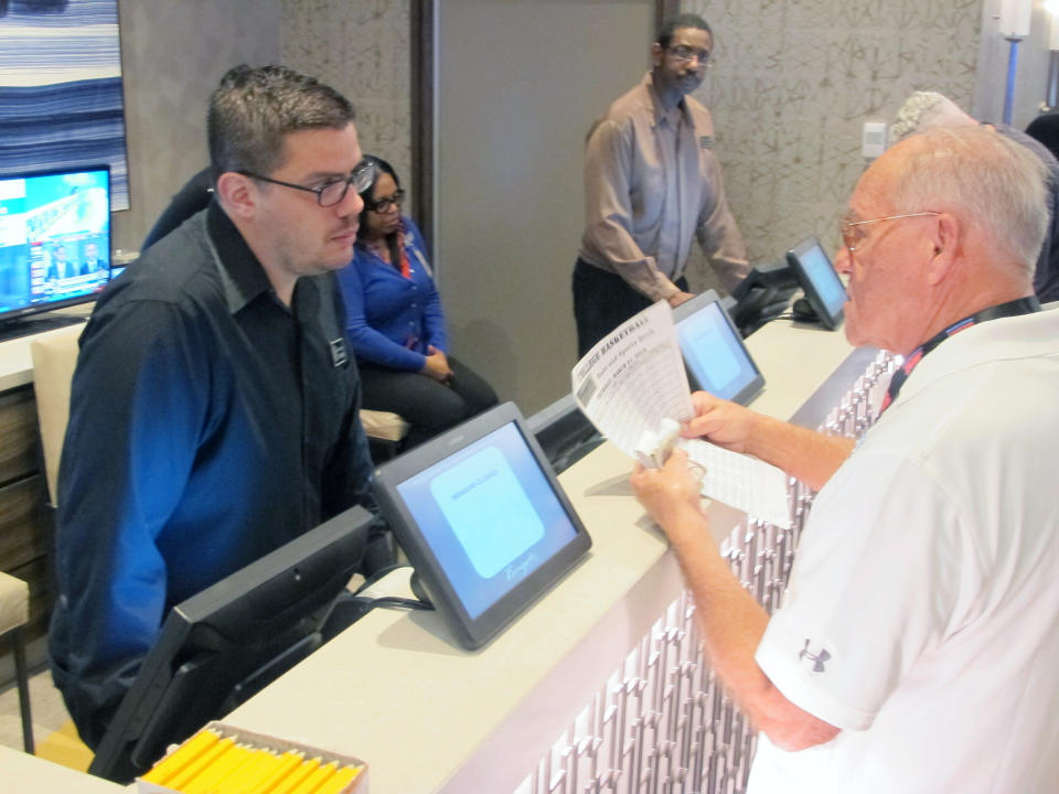 Jimmy Cliff, of Lewes, Del., talks to a worker about betting on the NCAA college basketball tournament Thursday, March 21, 2019, at the Borgata casino in Atlantic City N.J. College basketball fans are lining up at casinos and racetracks, and furiously tapping smartphone screens to get down bets on the March Madness college basketball tournament, in many states where it is legal for the first time. (AP Photo/Wayne Parry)