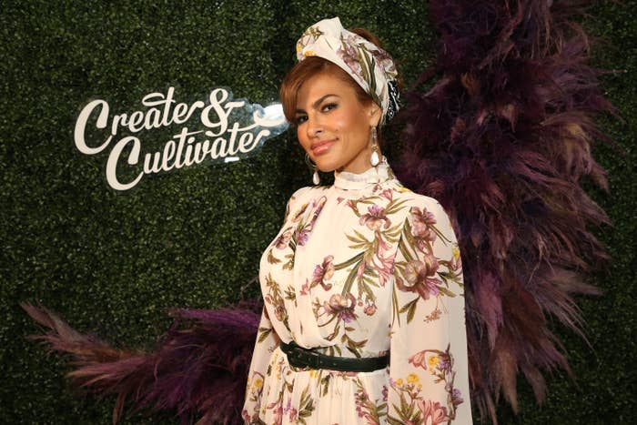 Eva smiles at an event while wearing a floral print dress with longs sleeves and a matching headscarf