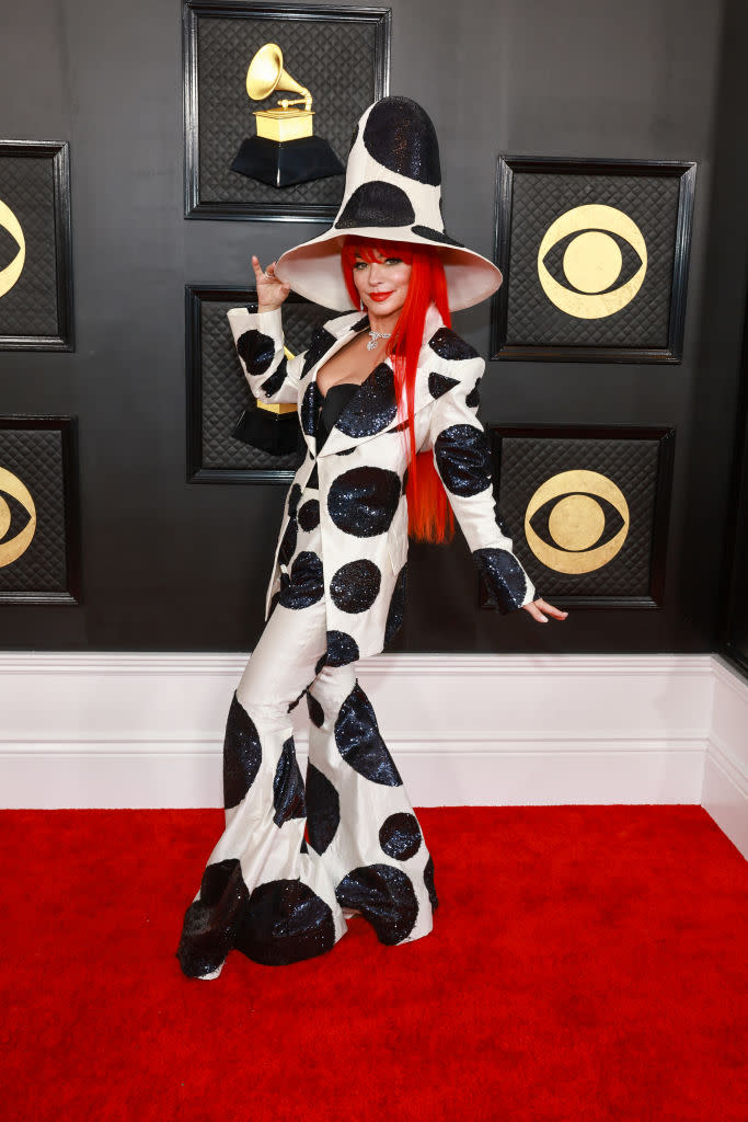Shania Twain in long red hair and white gown and hat with huge black spots.