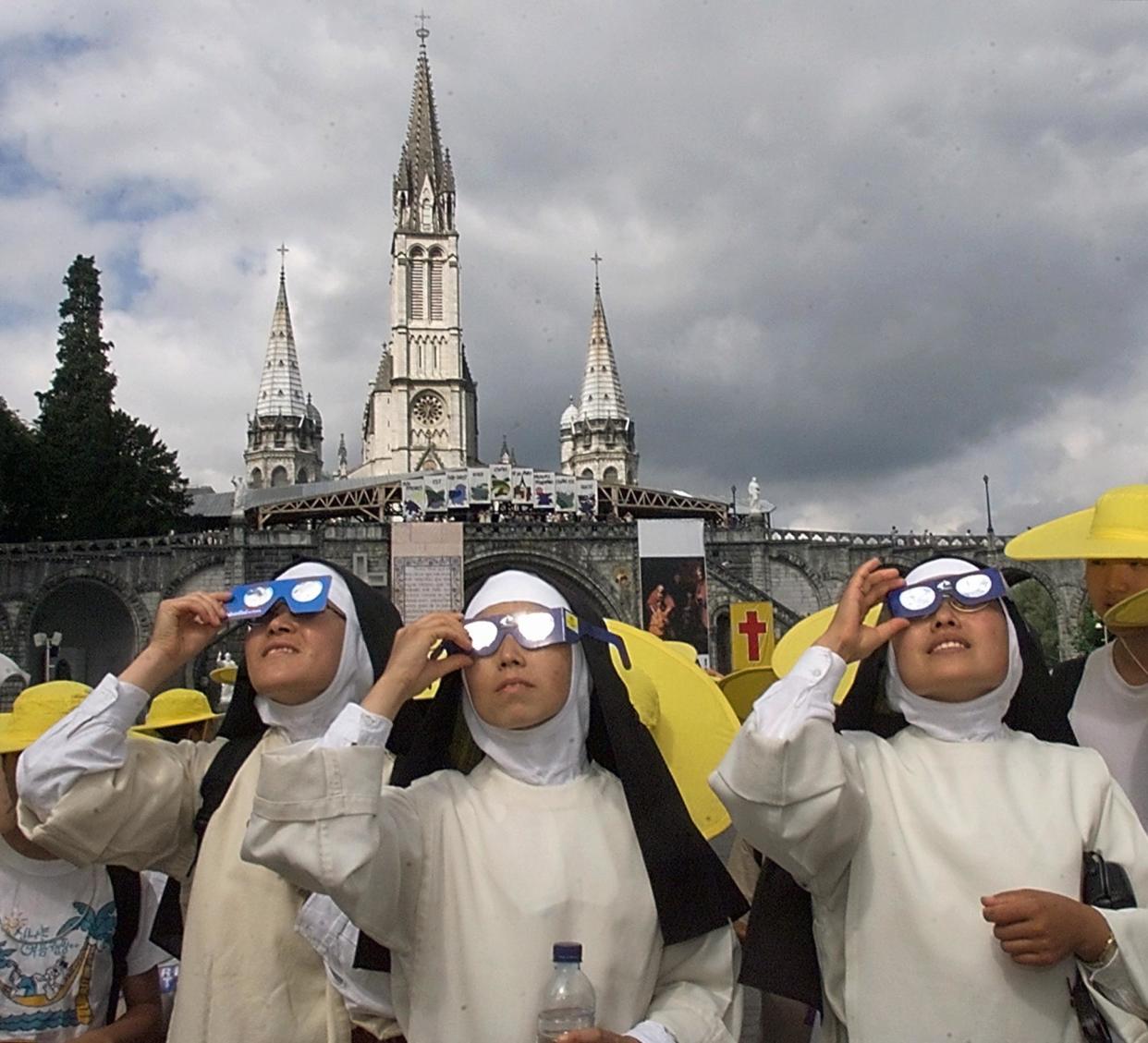 1999: Peruvian sisters take a break during their pilgrimage to view the solar eclipse in front of Notre Dame de Lourdes in France.