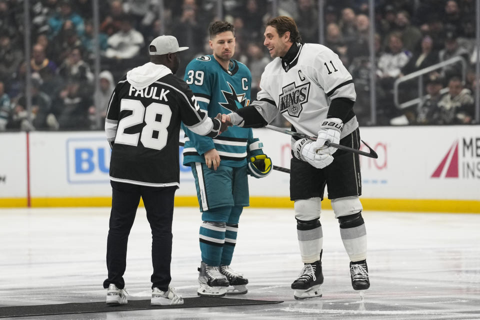 Former Los Angeles Rams running back Marshall Faulk, left, greets San Jose Sharks center Logan Couture (39) and Los Angeles Kings center Anze Kopitar (11) before their NHL hockey game Monday, Jan. 22, 2024, in Los Angeles. (AP Photo/Ashley Landis)