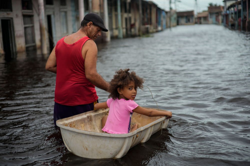 Jesus Hernandez guides his granddaughter Angelina via a container through a street flooded in the passing of Hurricane Helene, in Batabano, Mayabeque province, Cuba, on Sept. 26.<span class="copyright">Ramon Espinosa—AP</span>