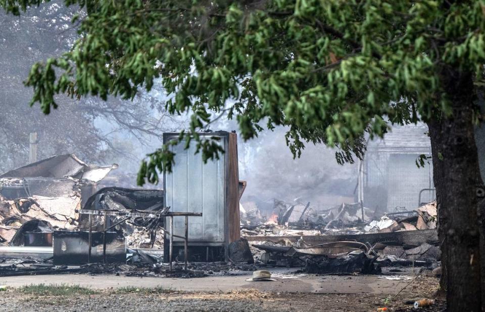 The remains of a structure burned the Park Fire smolder along Cohasset Road east of Chico on Thursday.