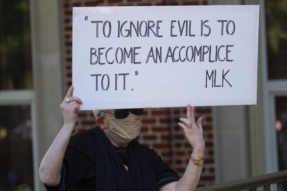A person holds a sign while watching a rally to protest the shooting of an unarmed black man Friday, May 8, 2020, in Brunswick Ga. Two men have been charged with murder in the February shooting death of Ahmaud Arbery, whom they had pursued in a truck after spotting him running in their neighborhood. (AP Photo/John Bazemore)