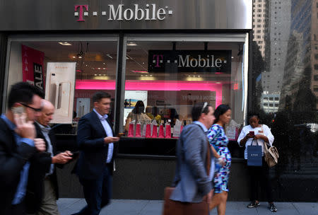 FILE PHOTO: Pedestrians use their smart phones as they pass a T-Mobile retail store in Manhattan, New York, U.S., September 22, 2017. REUTERS/Darren Ornitz