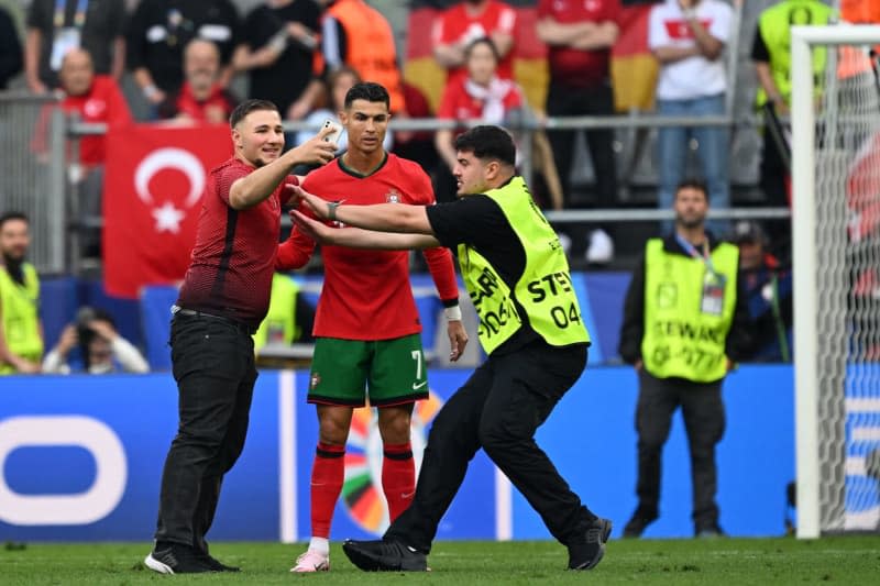 A pitch invader takes a selfie with Portugal's Cristiano Ronaldo during the UEFA Euro 2024 Group F soccer match between Turkey and Portugal at the Signal Iduna Park in Dortmund. Bernd Thissen/dpa