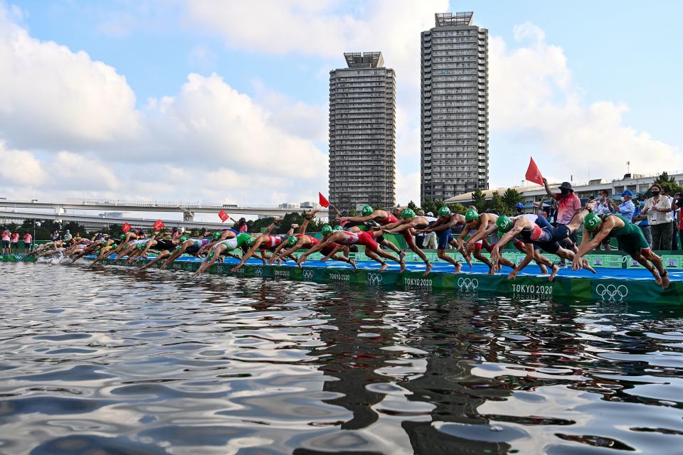 <p>Athletes compete in the men's individual triathlon competition during the Tokyo 2020 Olympic Games at the Odaiba Marine Park in Tokyo on July 26, 2021. (Photo by Loic VENANCE / AFP) (Photo by LOIC VENANCE/AFP via Getty Images)</p> 