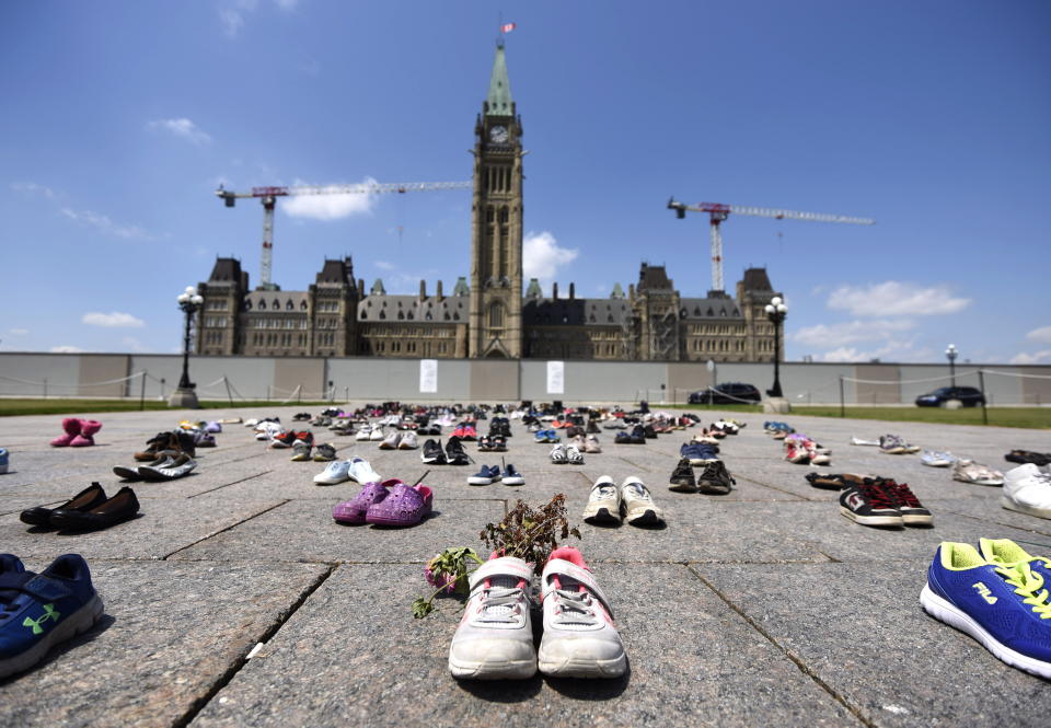 Dried flowers rest inside a pair of child's running shoes at a memorial for the 215 children whose remains were found at the grounds of the former Kamloops Indian Residential School at Tk'emlups te Secwépemc First Nation in Kamloops, B.C., on Parliament Hill in Ottawa on Friday, June 4, 2021. (Justin Tang/The Canadian Press via AP)