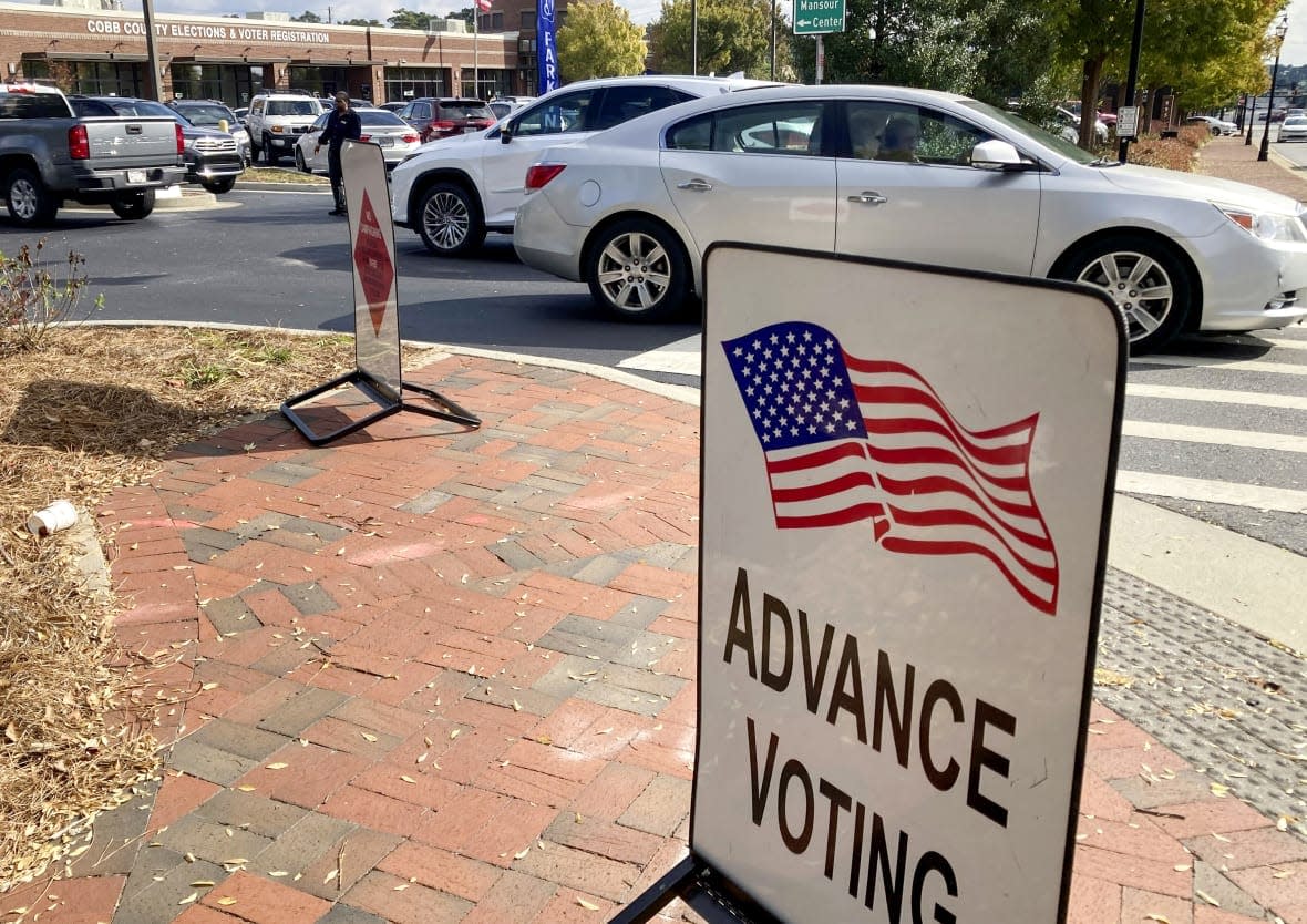 A sign showing the way for voters stands outside a Cobb County voting building during the first day of early voting, Oct. 17, 2022, in Marietta, Ga. (AP Photo/Mike Stewart, File)