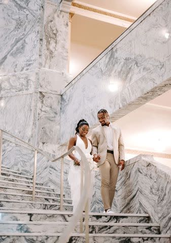 RAETAY PHOTOGRAPHY Simone Biles and husband Jonathan Owens descending marbled staircase on their wedding day in April 2023.
