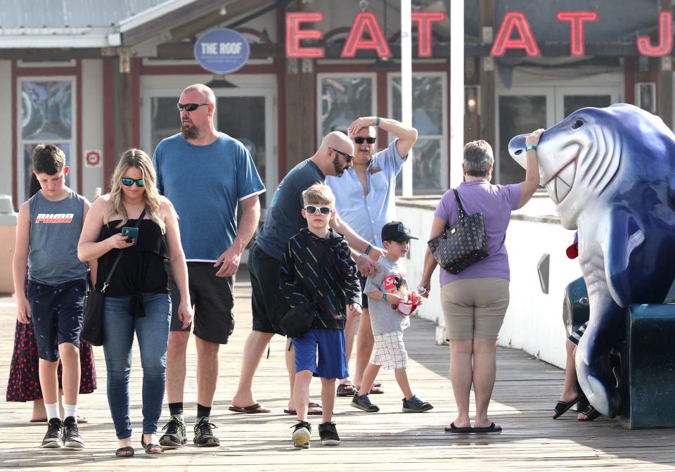 Families move past the big fiberglass shark on the pier on March 23, 2021, in Daytona Beach, Fla.