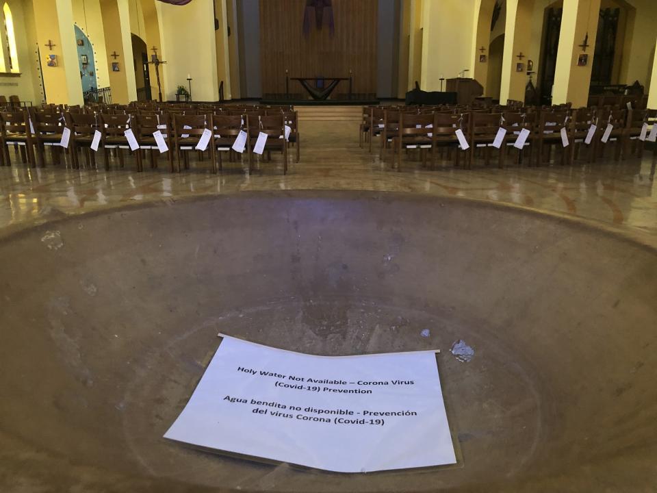 In this Saturday, March 14, 2020 photo, a sign reads, "Holy Water Not Available" in the baptismal font of the St. Stephen and the Incarnation Episcopal Church in Washington, which is closed due to the coronavirus pandemic. (AP Photo/Federica Narancio)