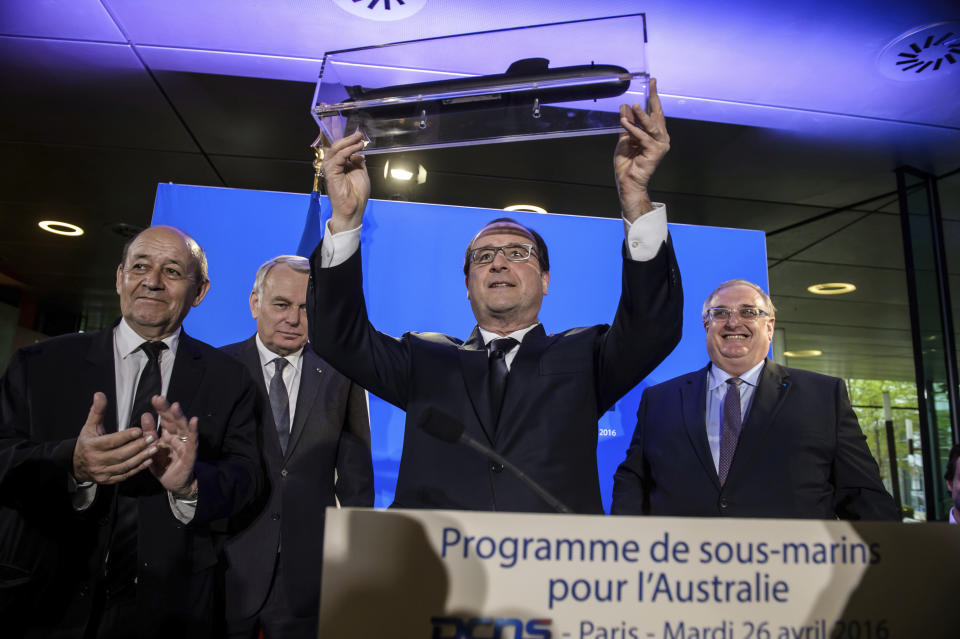 FILE - In this Tuesday, April 26, 2016 file photo, French President Francois Hollande, center, shows off a model of a submarine given by DCNS CEO Herve Guillou, right, in Paris, France. A round of free trade talks between the European Union and Australia has been postponed in the wake of a dispute over Canberra's decision to cancel a multibillion-euro French submarine deal. The 12th round of talks was scheduled to take place later this month. Australia had signed the 90 billion Australian dollar ($66 billion) deal in 2016 with French majority state-owned Naval Group in 2016 to build 12 conventional diesel-electric submarines. But Australia canceled the deal last month as part of an alliance with the United States and Britain. (Christophe Petit Tesson/Pool Photo via AP, File)