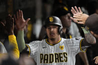 San Diego Padres' Manny Machado is greeted in the dugout after scoring from second base off a fielding error by Cincinnati Reds left fielder Spencer Steer during the fifth inning of a baseball game, Tuesday, April 30, 2024, in San Diego. (AP Photo/Gregory Bull)