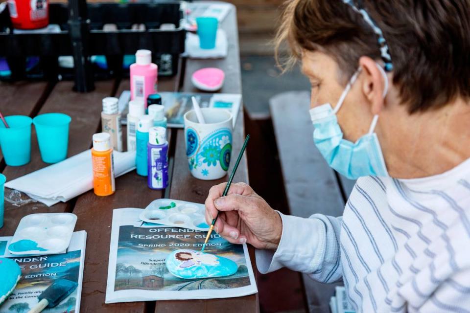 Interfaith Sanctuary resident Sherri paints an image of an angel on a rock as part of a memorial project for a fellow resident at the homeless shelter who was unvaccinated and died from COVID-19.