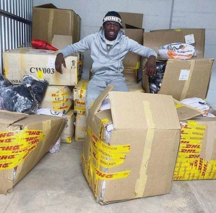 Quinton Dorsey sitting with boxes of clothing he designed for his business, Bag Season.