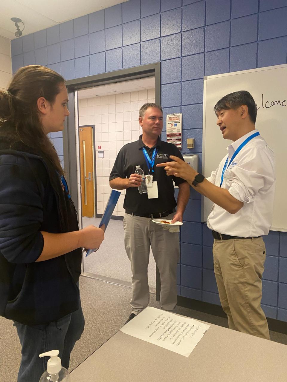 Faculty Ks Ku on right discusses IT careers with a DACC staff member and student.