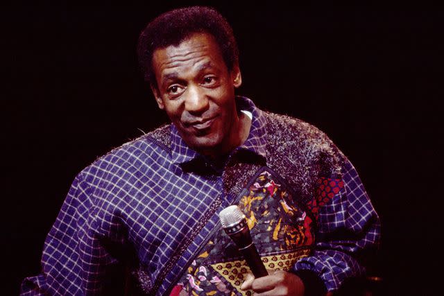 <p>Gary Gershoff/Getty </p> Bill Cosby performing onstage on Jan. 31, 1986