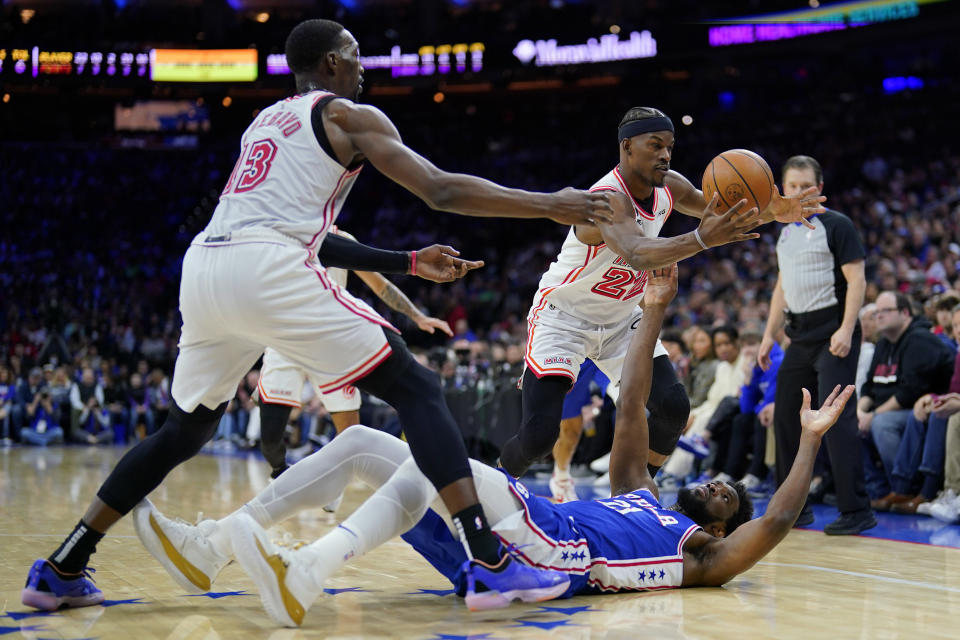 Philadelphia 76ers' Joel Embiid, bottom, and Miami Heat's Jimmy Butler, right, and Bam Adebayo chase a loose ball during the first half of an NBA basketball game, Monday, Feb. 27, 2023, in Philadelphia. (AP Photo/Matt Slocum)