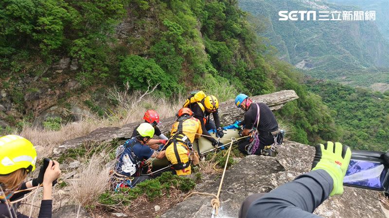 第一具卡在山壁上的遺體為彭女，被以人工搬運方式接力送上直升機運送下山。（圖／翻攝畫面）