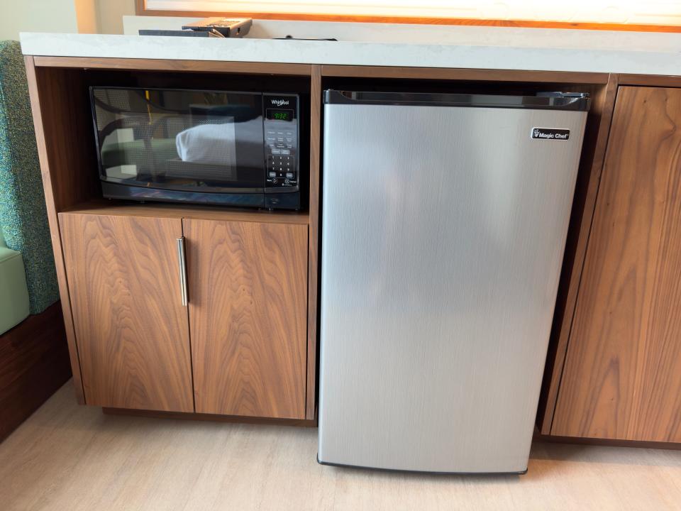 Microwave and miniature fridge in Disneyland duo studio next to wooden cabinets