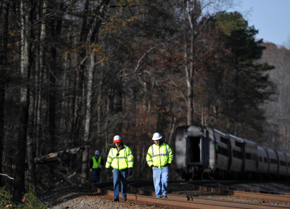 Workers walk on the tracks after the Amtrak Crescent train derailed, Monday, Nov. 25, 2013, in Spartanburg County, S.C. Several cars of the New York City-bound train with 218 people aboard went off the tracks early Monday as bags flew and jolted passengers clung to each other, authorities and passengers said. There were no serious injuries. (AP Photo/Rainier Ehrhardt)