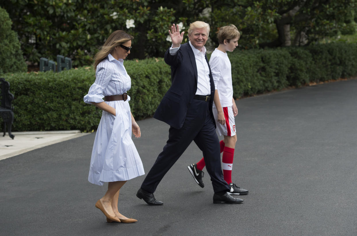 Melania Trump, pictured with President Trump and Barron Trump, wore a white belted dress on the way to Camp David in 2017. (Photo: Getty Images)